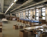 Werkhalle mit Tischen, Stuehlen und Kartons