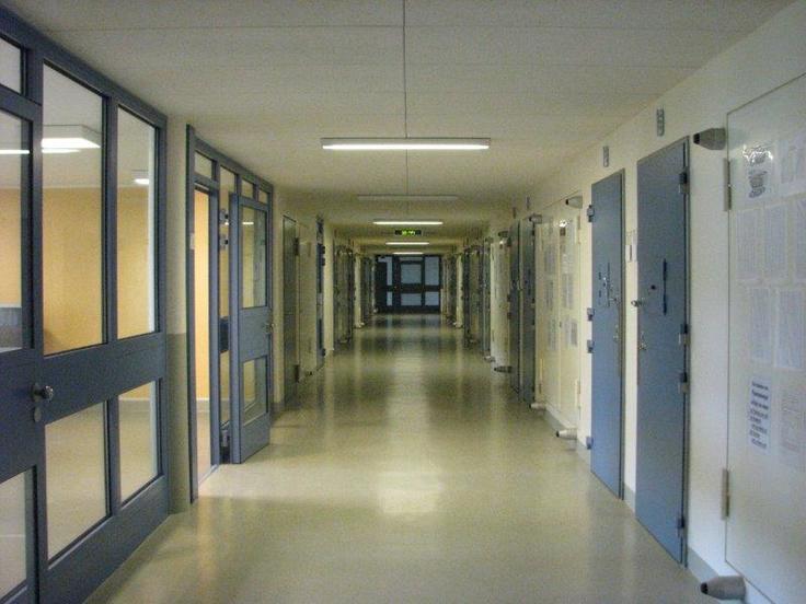 Blick auf den langen Haftflur mit blauen Türen